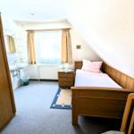 Ein Schlafzimmer mit Bett, Kleiderschrank und Bad. Dachneigung und Fenster sichtbar.