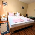 Schlafzimmer mit Doppelbett, Holzboden und Fenster mit Vorhängen.