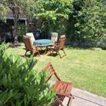 Hinterhof mit Garten, Tisch und Stühlen. Grünfläche, Bäume und Pflanzen.