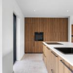 Moderne Küche mit Holzschränken, Edelstahlspüle und integriertem Ofen.