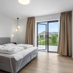 Schlafzimmer mit Bett, TV und Balkonblick.