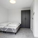 Schlafzimmer mit zwei Matratzen, Kleiderschrank und Bodenfliesen.