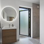 Badezimmer mit Waschbecken, Spiegel und Tür zur Terrasse.