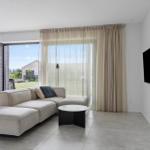 Wohnzimmer mit Sofa, Kamin und großem Fenster zur Außenterrasse.
