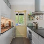 Kitchen with white cabinets, dark countertop, and window to the garden.
