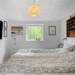 Bedroom with bed, window, wall shelf, and ceiling light.