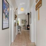 Hallway with wooden floor, wall art, and fireplace in the background.