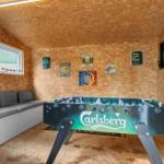 Room with foosball table, sofa, and wall decorations made of wood.