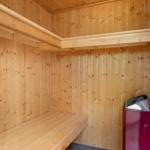 Sauna with wooden cladding, bench, and heater.