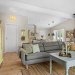 Living room with gray sofa, wooden floor, and dining area in the background.