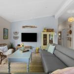 Living room with sofa, coffee table, and TV. Window with view of garden.