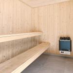 Sauna mit Holzwand und Sitzbänken, Heizung mit Steinen an der Wand.