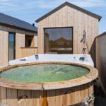 Haus mit Holzverkleidung, Whirlpool und Holzbadewanne auf Terrasse.