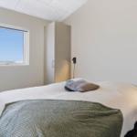 Schlafzimmer mit Bett, Fenster und Schrank. Blick auf den Himmel.