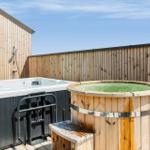 Außenbereich mit Whirlpool und Holzbadewanne auf Terrasse.