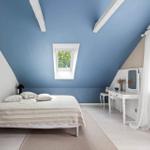 Schlafzimmer mit blauem Dach, weißem Schrank, Bett und Schreibtisch.