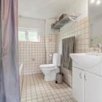 Badezimmer mit Badewanne, Toilette und Waschbecken mit Spiegel.