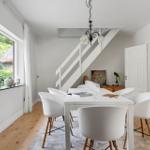 Esszimmer mit weißem Tisch, Stühlen und Fensterblick auf Garten
