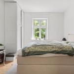 Schlafzimmer mit Bett, Fenster und Kleiderschrank. Holzboden und weiße Wände.