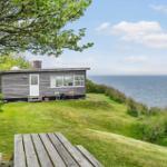 Kleines Haus mit Meerblick, Garten und Holztisch. Blick auf das Meer.