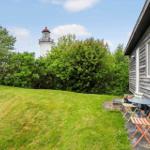Haus mit Terrasse, Garten und Blick auf Leuchtturm.