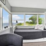 Schlafzimmer mit Blick auf Meer und Grünfläche. Bett, Sessel und Fenster sind sichtbar.