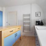 Küche mit blauen Schränken, Holzoberfläche und weißen Fliesen an der Wand.
