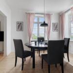 Esszimmer mit runder Tisch, vier Stühlen und Fenstern mit rosa Vorhängen.