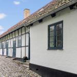 Ferienhaus mit weiß verputzter Fassade, dunklen Fenstern und Steinweg.