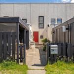 Haus mit roter Tür, gepflastertem Weg und schwarzen Holzgeländern.