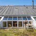 Haus mit Glasveranda, Tisch, Stühle und Vogelhaus im Vorgarten.