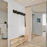 Flur mit Garderobe, Waschmaschine und Badezimmer im Hintergrund.
