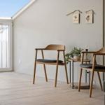 Ein Raum mit Holzstühlen, Tisch und Pflanze unter einem Dachfenster.