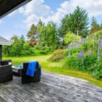 Terrasse mit Sitzgelegenheiten und Blick auf grünen Garten mit Lupinen.