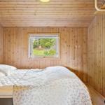 Schlafzimmer mit Holzwandverkleidung und Fenster zur grünen Außenseite.