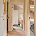 Hallenflur mit Blick in Schlafzimmer und Waschraum mit Waschmaschine.