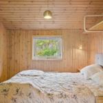 Schlafzimmer mit Holzwand, Bett, Fenster und Wandbild.