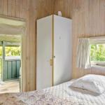 Schlafzimmer mit Bett, Kleiderschrank und Blick auf Balkon und Grün.