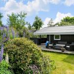 Haus mit Terrasse, Garten und blühenden Lupinen unter blauem Himmel.