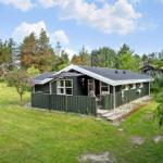 Ein grünes Ferienhaus mit Terrasse und Garten. Umgeben von Bäumen und Gras.
