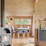 Wohnraum mit Holzwand, Esstisch, Kaminofen und Sideboard.