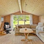 Wohnzimmer mit Holzwand, Sofa, Esstisch und Fernseher. Große Fenster mit Blick auf Grünflächen.