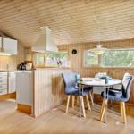 Küche mit Essbereich, Holzwand und -decke, runder Tisch mit blauen Stühlen.