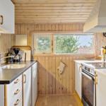 Küche mit Holzwand, Arbeitsplatte, Spüle, Herd und Fenster.