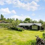 Ein kleines Haus mit grünem Garten und Bäumen unter blauem Himmel.