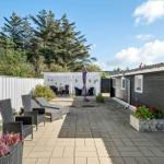 Terrasse mit Liegestühlen, Sonnenschirm und Gartenhaus neben einem Haus.