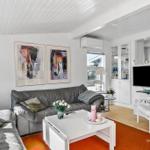 Wohnzimmer mit grauem Sofa, weißen Möbeln und zwei Wandbildern.