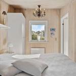 Schlafzimmer mit Holzwand, Bett, Fenster und Kronleuchter.