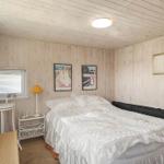 Schlafzimmer mit Holzwandverkleidung, Bett mit weißer Bettwäsche und Fenster mit Jalousie.