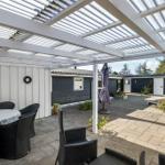 Terrasse mit Sitzgruppe unter Pavillon. Hintergrund: gepflasterter Hof mit Garten und Häusern.